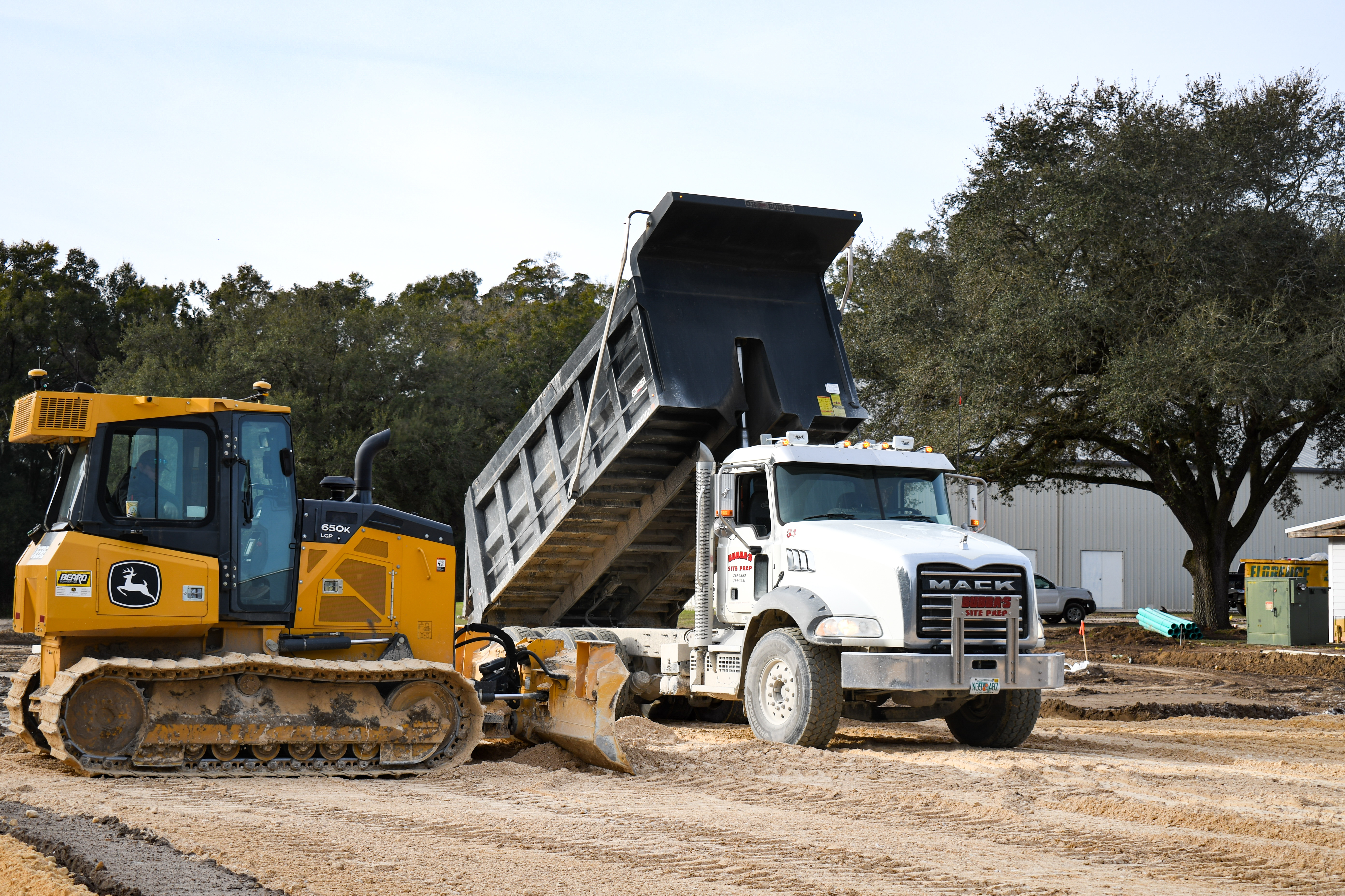 John Deere dozer and Mack dump truck on site prep — Lake City, FL
