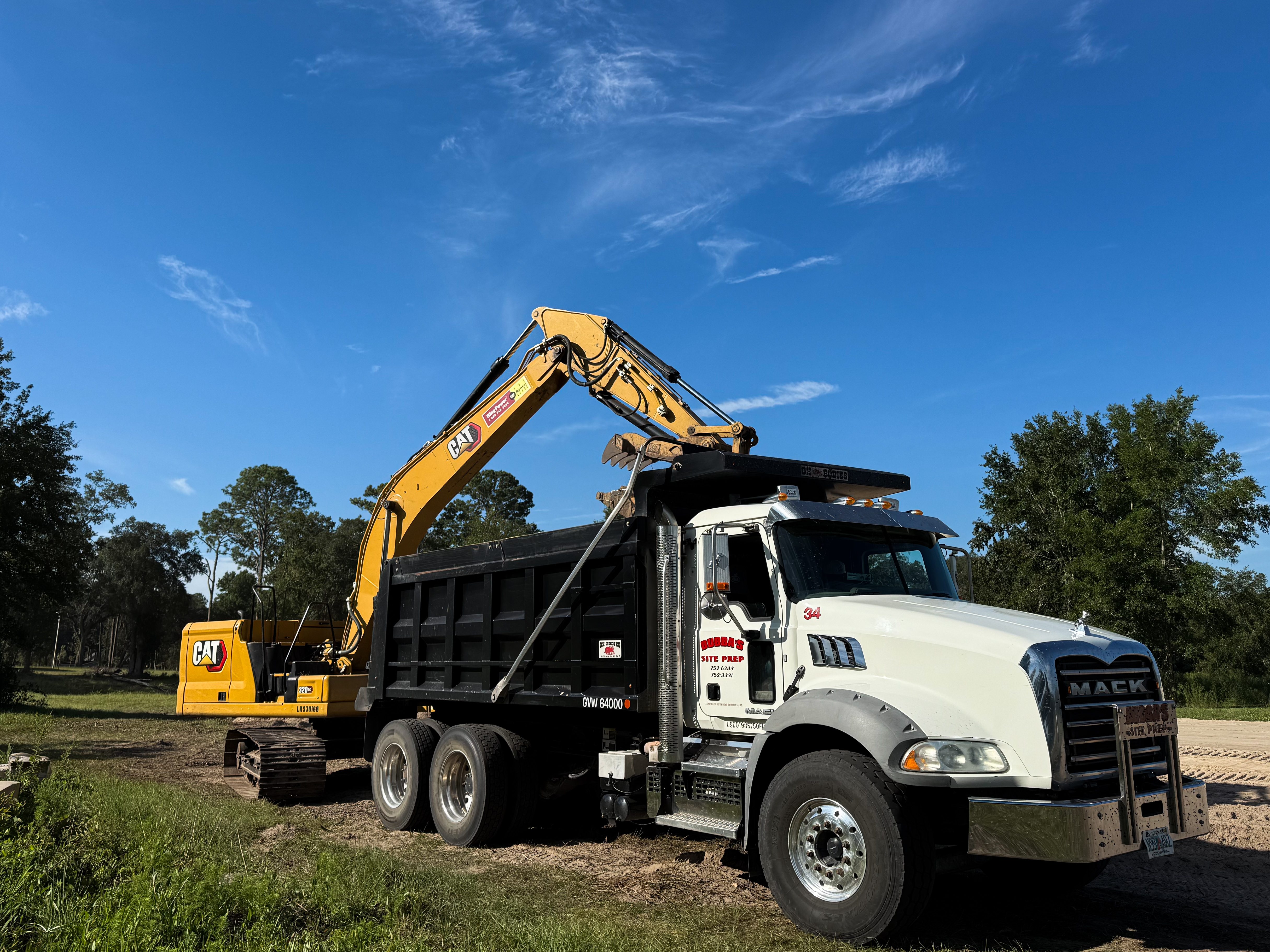 CAT excavator loading Bubba's Site Prep dump truck on job site in Lake City, FL